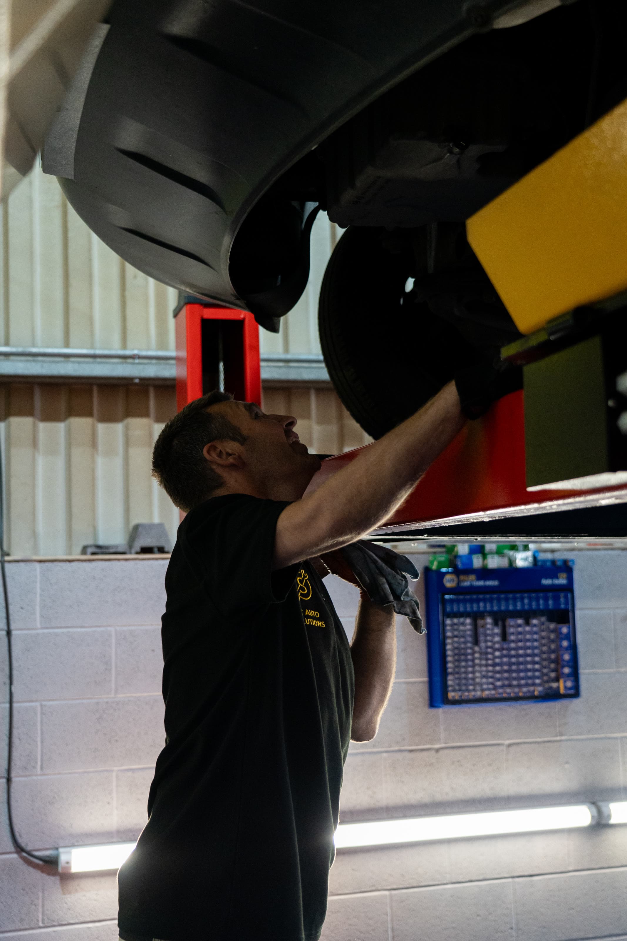 A technician working on the underside of a vehicle on the lift