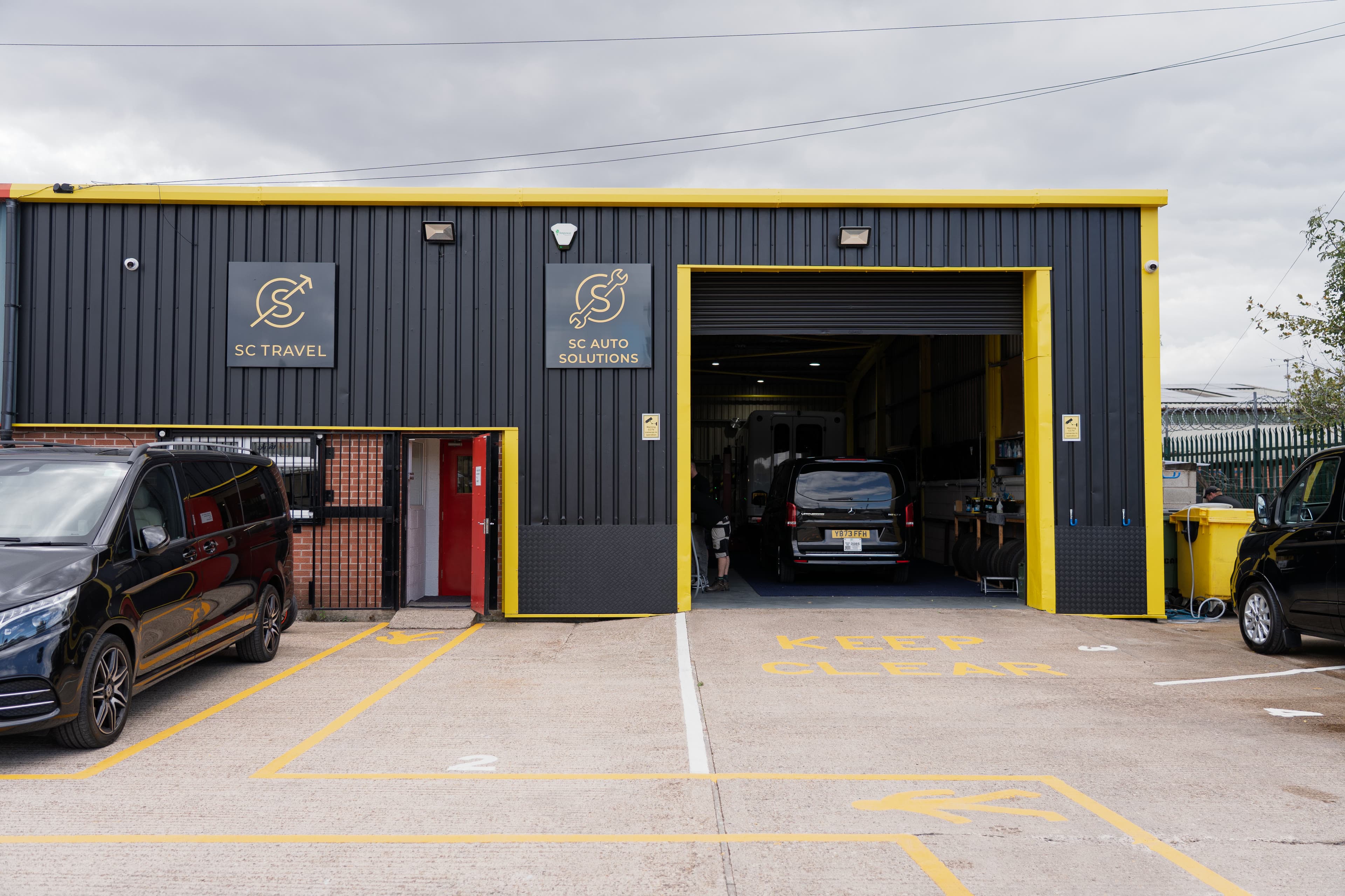 The SC Auto Solutions workshop front, roller door open with vehicles inside