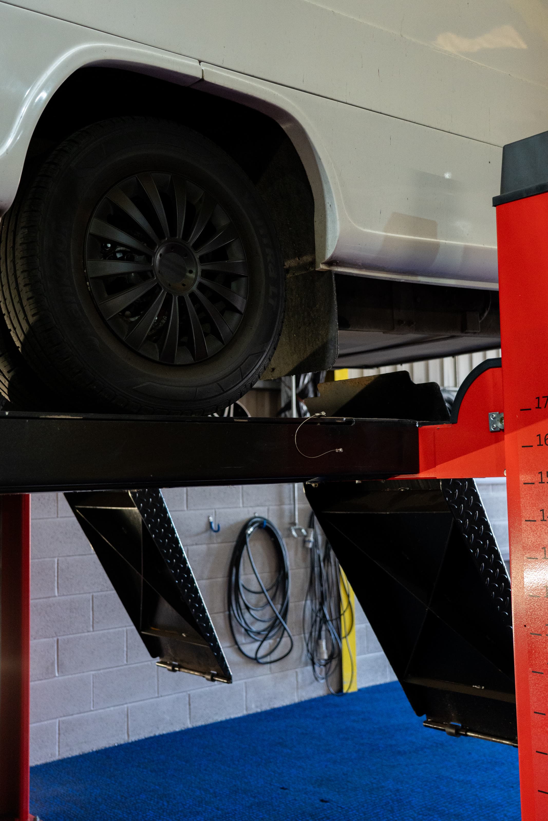A van wheel raised on the four-post lift